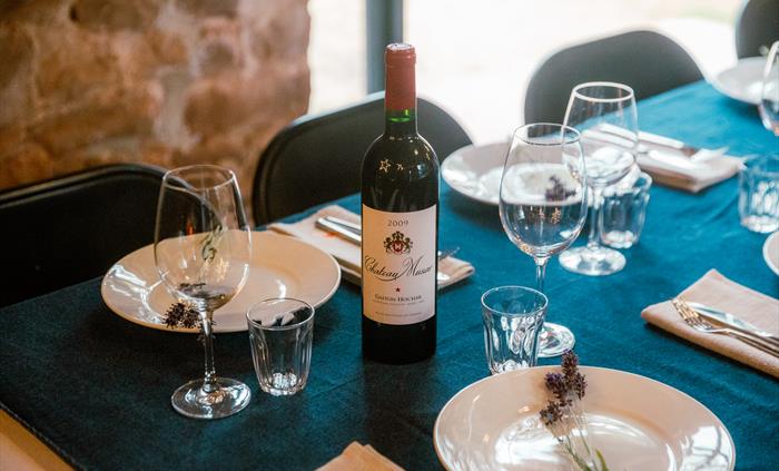 Close up of table laid for dining, bottle of wine, plates and glasses